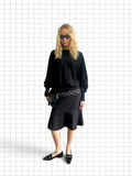 Wieder Wieder black long sleeve knit sweater with dropped shoulders and ribbed cuffs worn with a pinstripe skirt