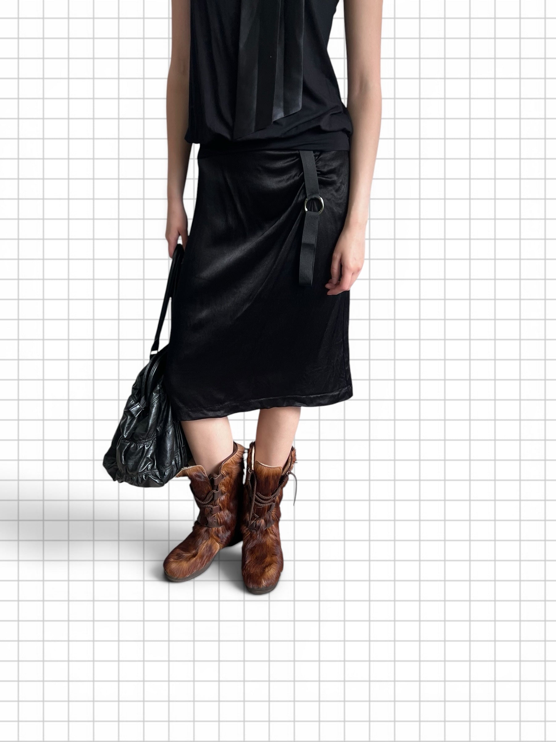 Wieder Wieder black midi skirt with side strap and metal ring detail, worn with brown fur boots and a black bag.