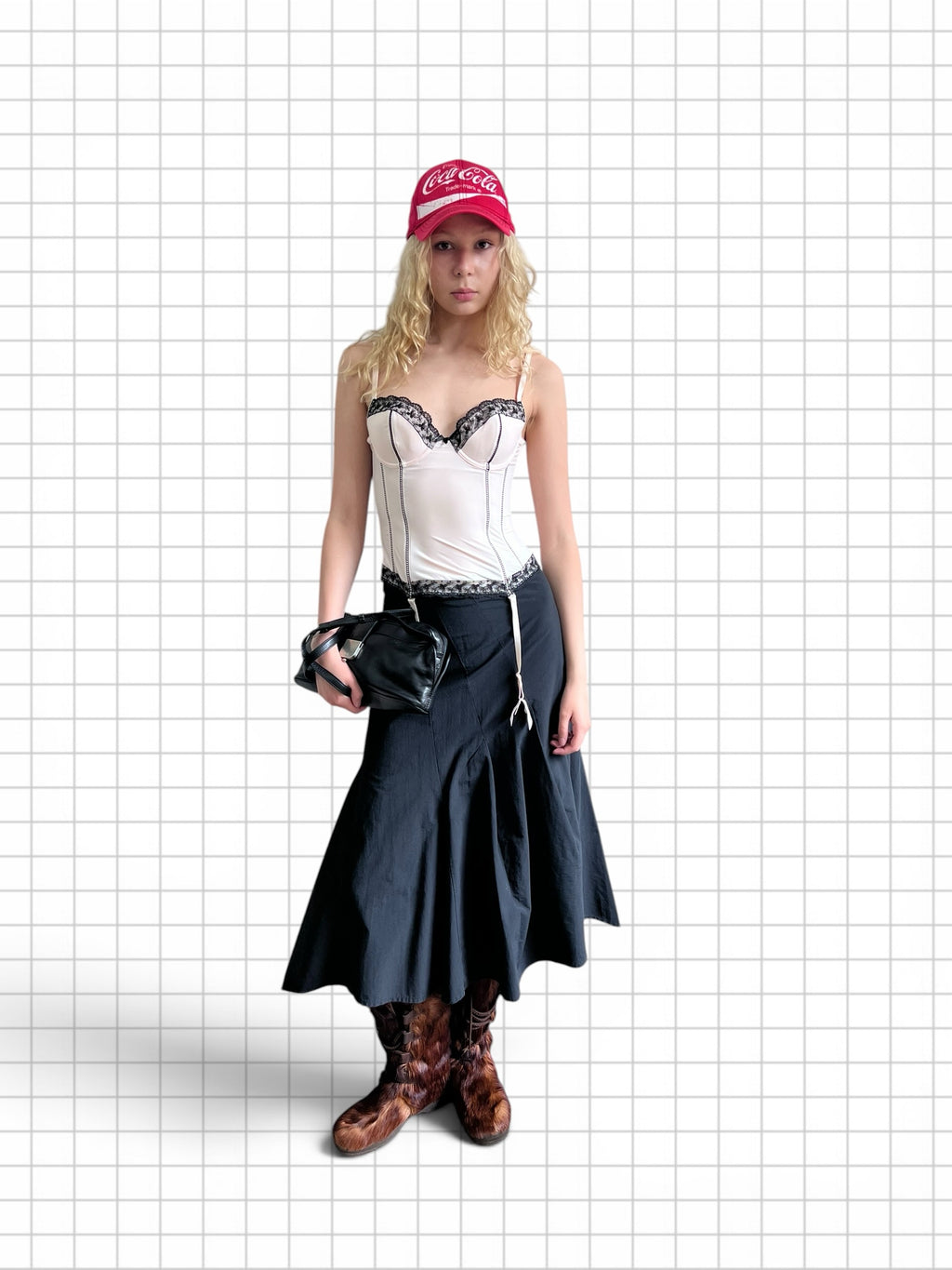 Wieder Wieder black midi skirt with suspender straps worn by a model with a white corset, red cap, and brown boots.