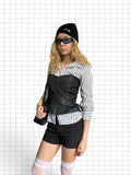Wieder Wieder black structured peplum corset top worn over a striped shirt by a blonde model with sunglasses and beanie