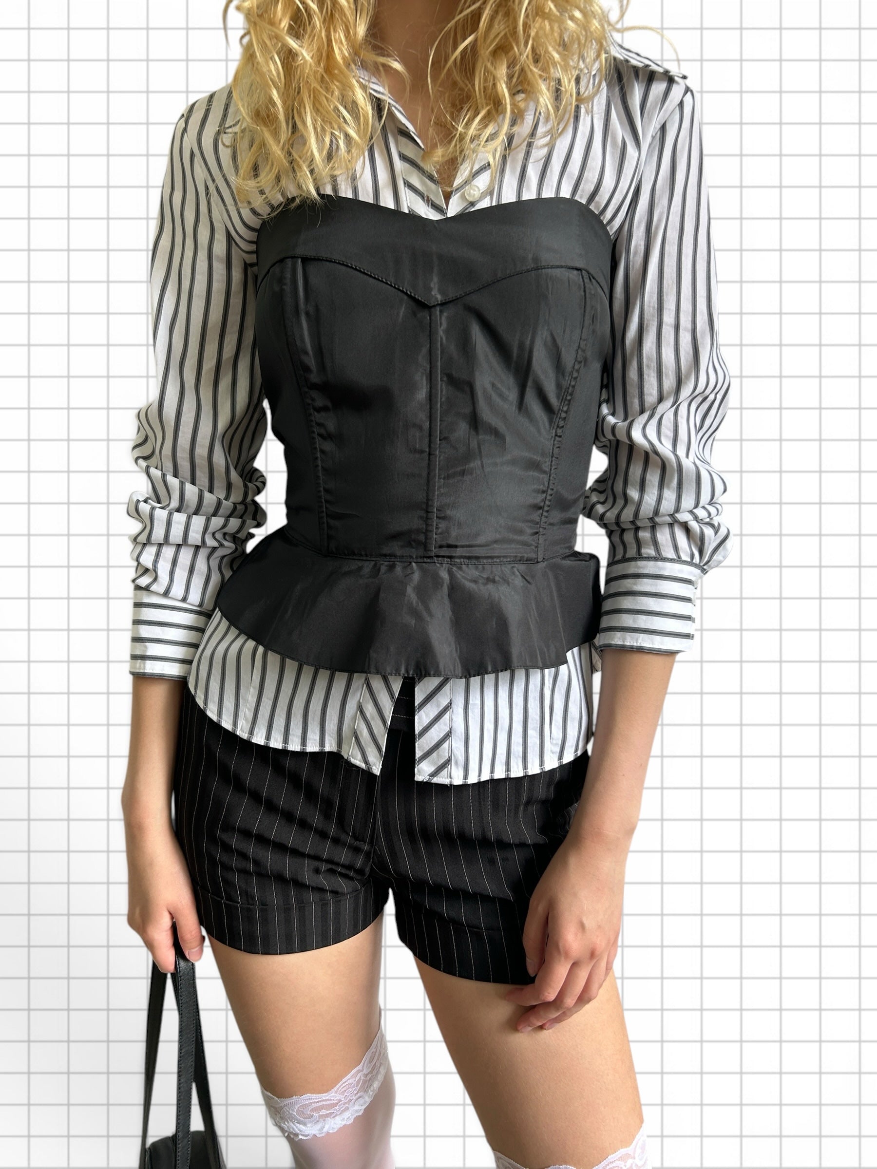 Wieder Wieder black structured peplum corset top worn over a striped button-down shirt with pinstripe shorts.