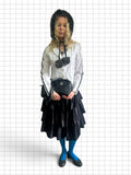 Wieder Wieder black tiered midi skirt with cascading ruffles worn by a model with a faux fur hat and blue tights.