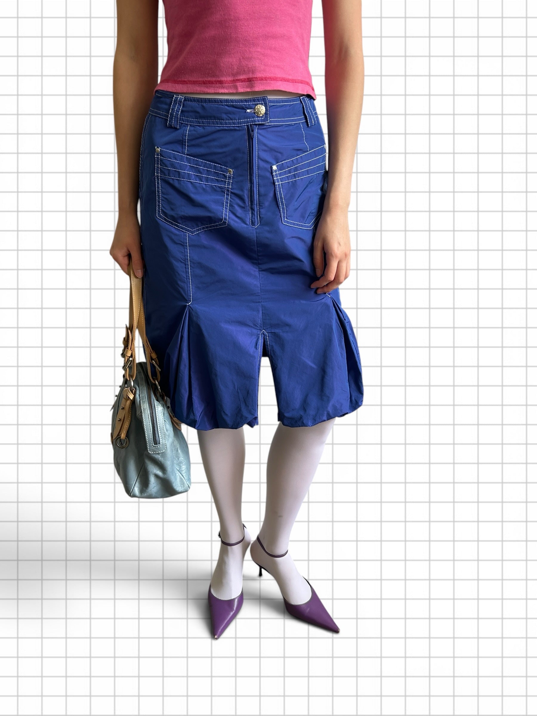 Wieder Wieder royal blue midi skirt with white contrast stitching, front pockets, and pleated hem worn with white tights.