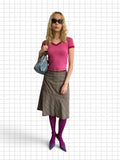 Wieder Wieder brown glen plaid midi skirt with asymmetrical hemline worn by a model with a pink top and purple tights