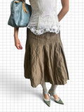 Wieder Wieder brown pleated midi skirt with contrast stitching and panel detailing worn with a white lace top.