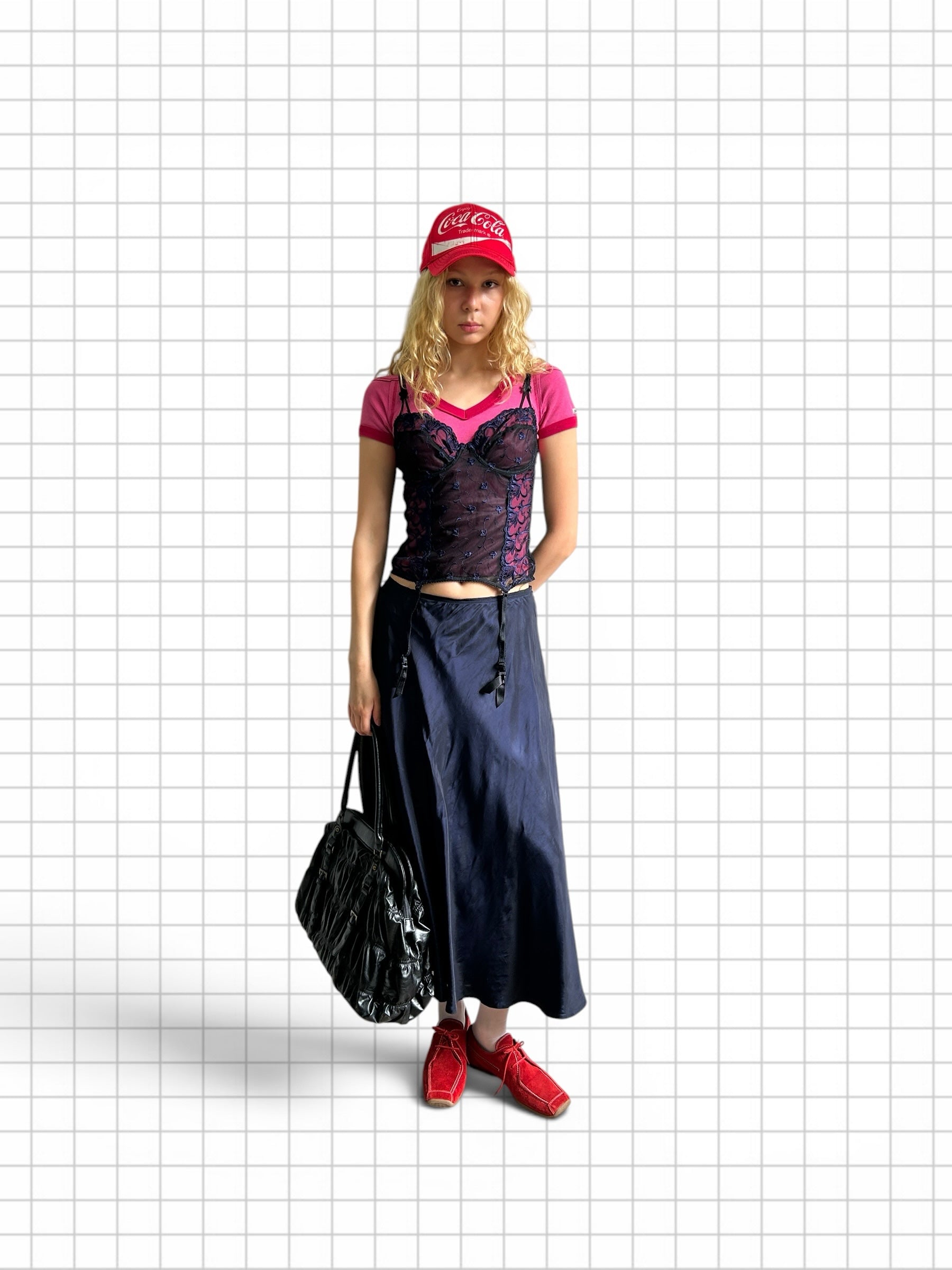 Wieder Wieder dark blue satin midi skirt with suspender straps worn by a model with a pink top and red accessories.