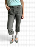 Wieder Wieder grey tailored cropped trousers with a button closure, worn with light grey leggings and pointed heels.