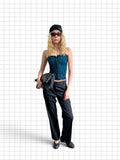 Wieder Wieder teal corset top with black floral lace overlay, worn by a blonde model with black trousers and beanie.